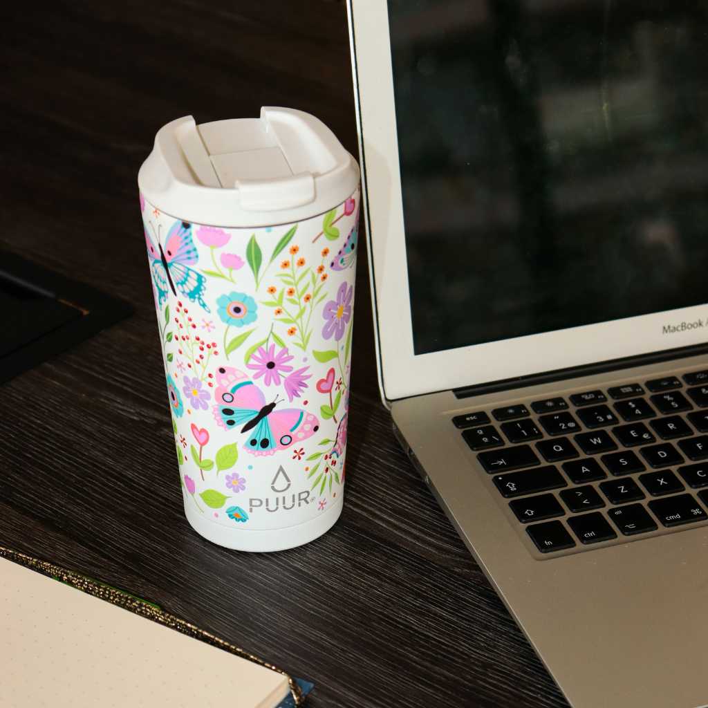 Vaso termico Puur 470ml con diseño de flores y mariposas en escritorio