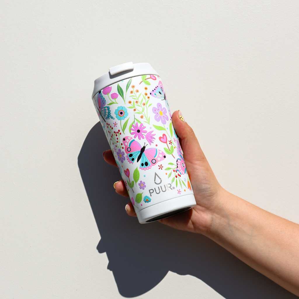 Mano con Vaso termico Puur 470ml con diseño de flores y mariposas en fondo blanco
