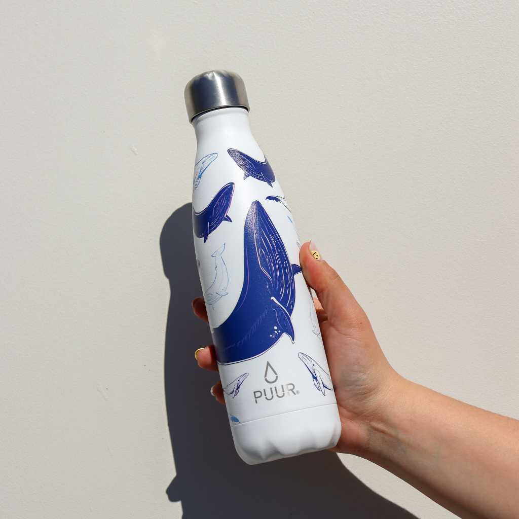 Mano con Botella termica Puur 500ml con diseño de ballenas en fondo blanco