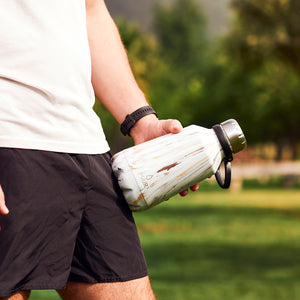 BOTELLA DE ACERO INOXIDABLE MAXI BOCA ANCHA BLANCO MARMOLEADA MARCA PUUR CON GANCHO EN MANOS DE HOMBRE DEPORTISTA